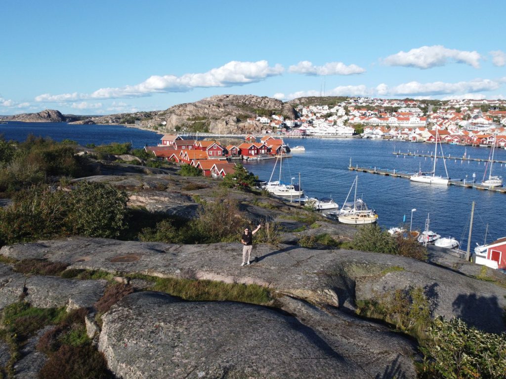 Melker Wångdahl standing on granite rocks on S:t Görans Ö with Hunnebostrand harbour and sailboats in the background.